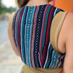  A woman wearing the blue Rustic Stripe Fitted Vest with a tan tank and striped pants
