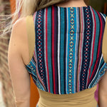 A woman wearing the blue Rustic Stripe Fitted Vest with a tan tank and striped pants.