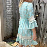 A woman wearing the Blue Crepe Thread Embroidered & Lace Decorated Dress in front of a wooden fence.