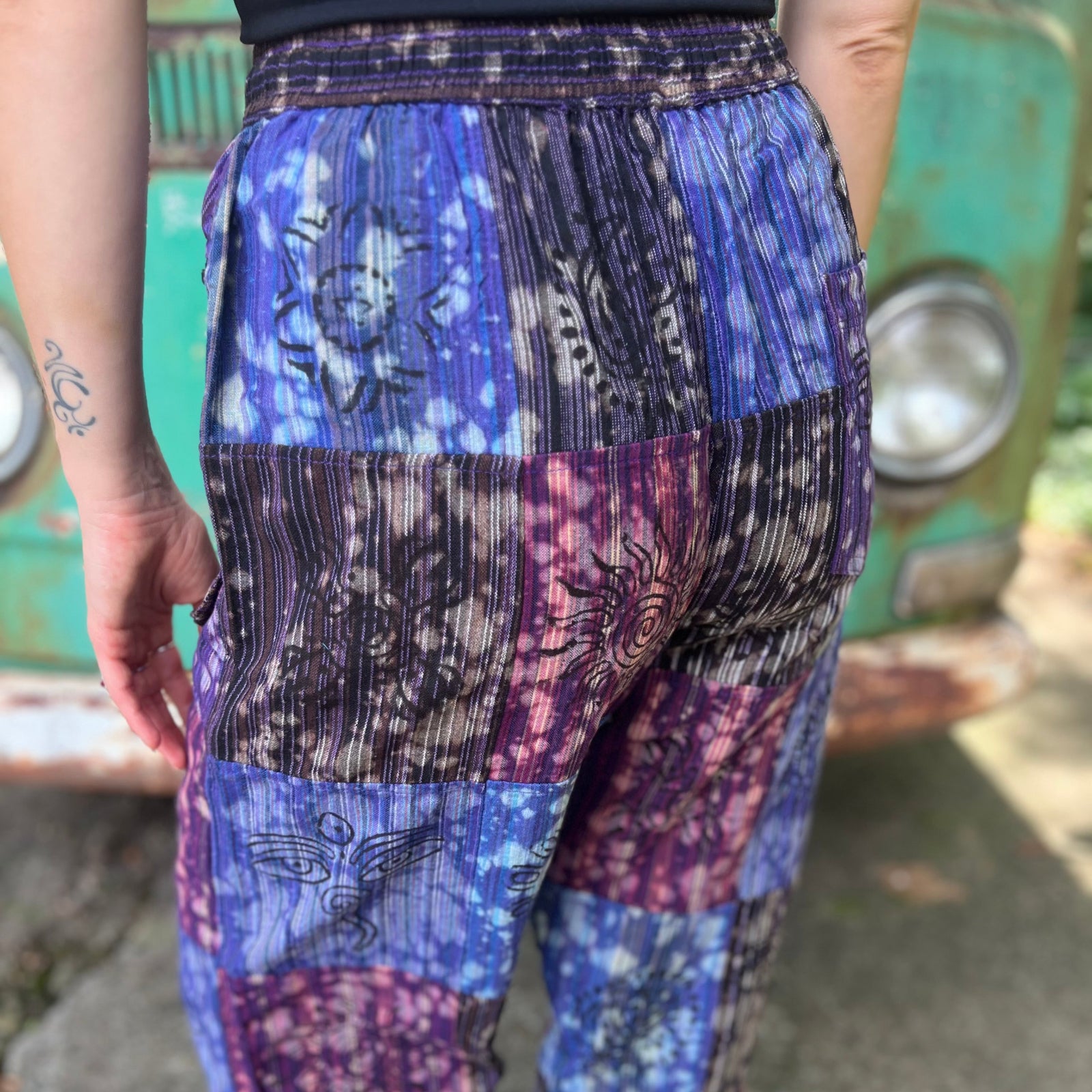 A woman wearing the Cotton Block Print Batik Cutwork Pants in front of a vintage Volkswagen bus.