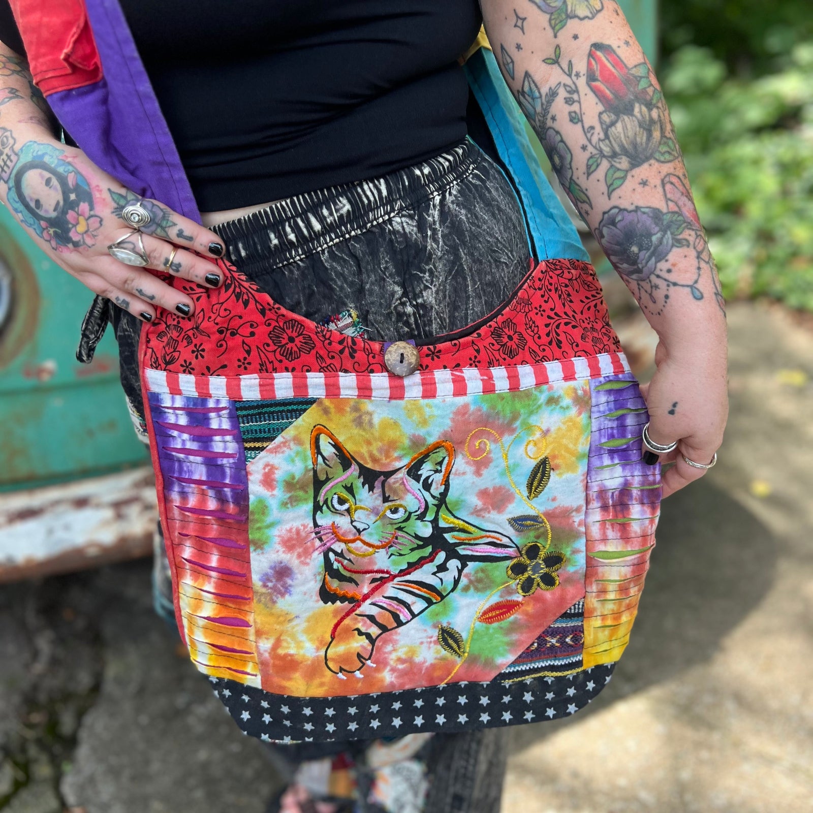 An up-close image of someone wearing the Cotton Tie Dye Cat Crossbody Bag in front of the vintage Volkswagen bus.