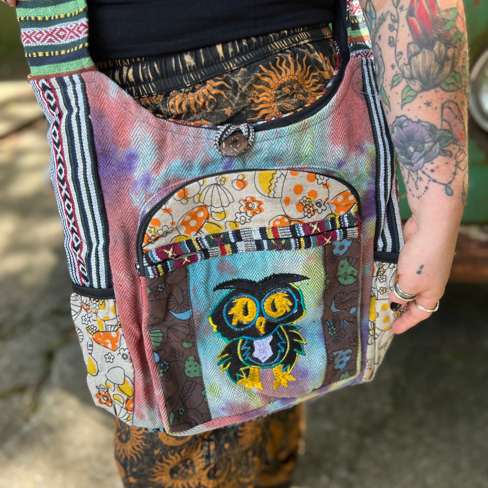 An up-close image of someone wearing the Tie Dye Owl with Mushroom Cotton & Hemp Pocket Bag in front of a vintage Volkswagen bus.
