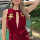 A woman wearing the burgundy Suede Sequin Embellished Embroidered Bootcut Jumpsuit in front of a teal vintage Volkswagen bus.
