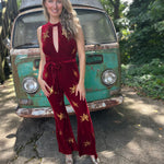 A woman wearing the burgundy Suede Sequin Embellished Embroidered Bootcut Jumpsuit in front of a teal vintage Volkswagen bus.