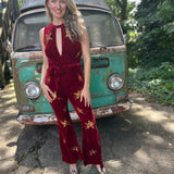 A woman wearing the burgundy Suede Sequin Embellished Embroidered Bootcut Jumpsuit in front of a teal vintage Volkswagen bus.