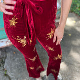 A woman wearing the burgundy Suede Sequin Embellished Embroidered Bootcut Jumpsuit in front of a teal vintage Volkswagen bus.