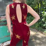 A woman wearing the burgundy Suede Sequin Embellished Embroidered Bootcut Jumpsuit in front of a teal vintage Volkswagen bus.