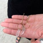 Someone is holding the brass Quartz Crystal Drop Earrings.