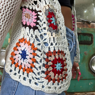 An up-close image of someone wearing the Bohemian Rainbow Crochet Cardigan in front of an old teal Volkswagen bus.