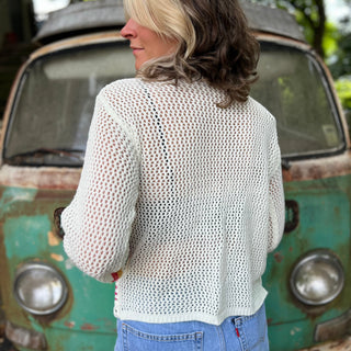 The back of someone wearing the Bohemian Rainbow Crochet Cardigan in front of an old teal Volkswagen bus.