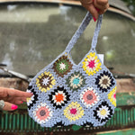 Someone holding the blue Bohemian Handmade Crochet Bag in front of a teal Volkswagen bus.