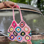 Someone holding the pink Bohemian Handmade Crochet Bag in front of an old teal Volkswagen bus.