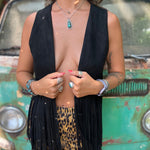 A woman wearing the black Western Open Soft Suede Fringe Vest and animal print pants.