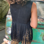 A woman wearing the black Western Open Soft Suede Fringe Vest and animal print pants.