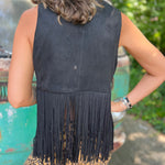 A woman wearing the black Western Open Soft Suede Fringe Vest and animal print pants.