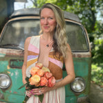 A woman wearing the cream Retro Sunburst Suede Color Block Long Fringe Faux Vest and holding a bouquet.