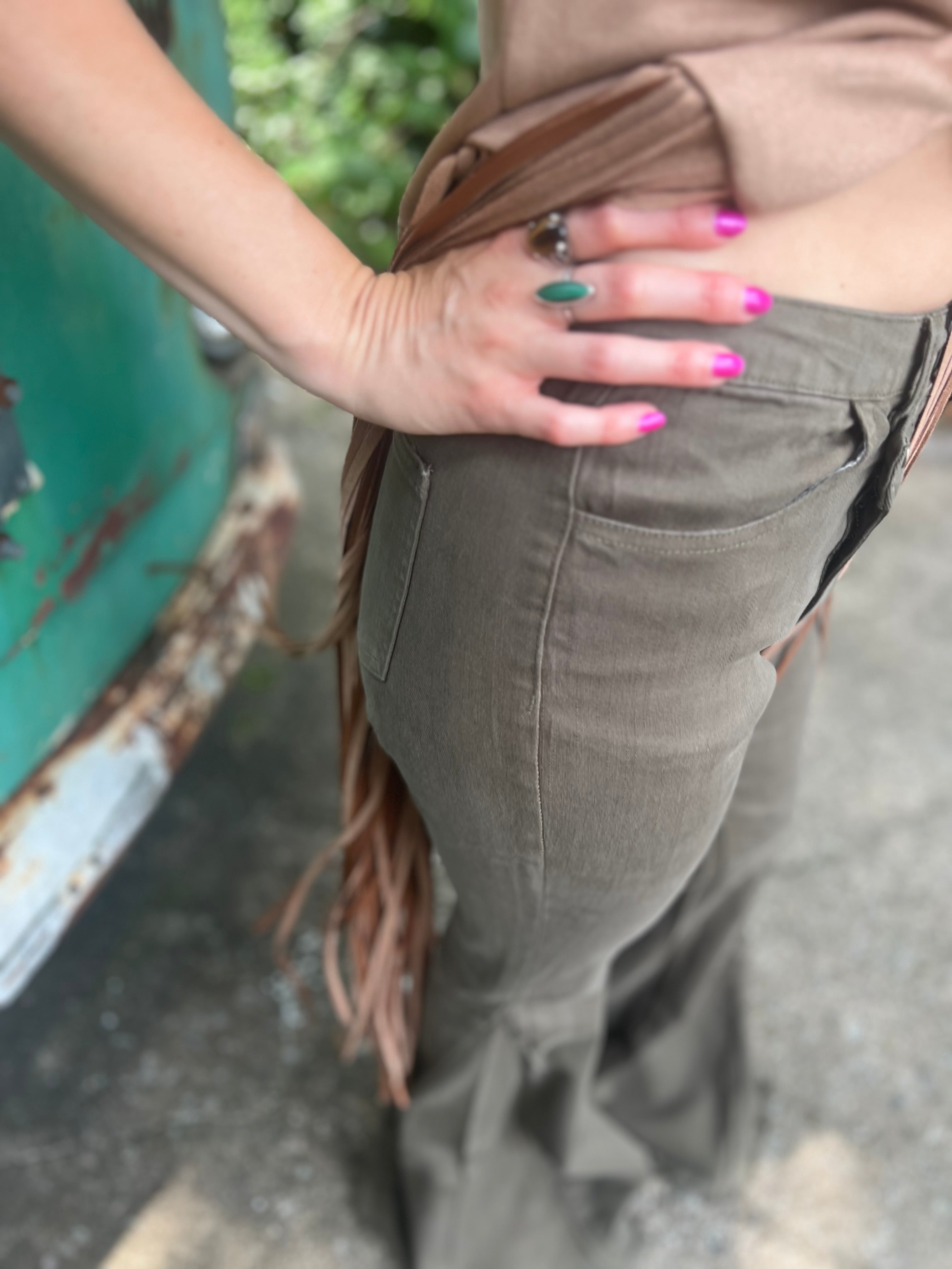Someone wearing the Olive Criss Cross Upsized Bell Bottom Jean with a fringe vest.