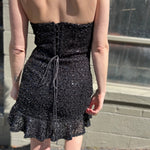 A woman wearing the espresso Sequin Lace-Up Back Strapless Mini Dress.
