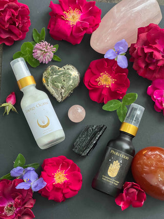 Flowers and healing crystals scattered around aromatherapy bottles.