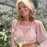 Close-up of woman in boho pink crochet top with daisy flowers in the foreground