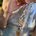 Someone holding the Sun and Moon Harlequin Collage Matte Fine Wrapping Paper in front of a vintage teal Volkswagen bus.