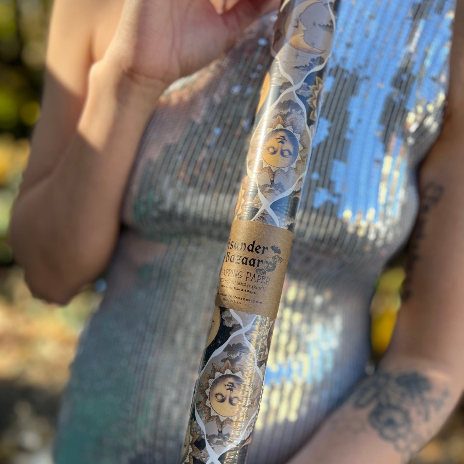 Someone holding the Sun and Moon Harlequin Collage Matte Fine Wrapping Paper in front of a vintage teal Volkswagen bus.