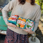 Someone holding three of the Tea Towel Sets from The Neighborgoods.