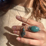 Someone wearing the Black Kyanite Electroformed Necklace with Turquoise and a beige sweater.