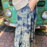 Someone wearing the indigo Tie Dye Gauze Cotton Skirt with a beige sweater in front of a vintage teal Volkswagen bus. Showing off the side.