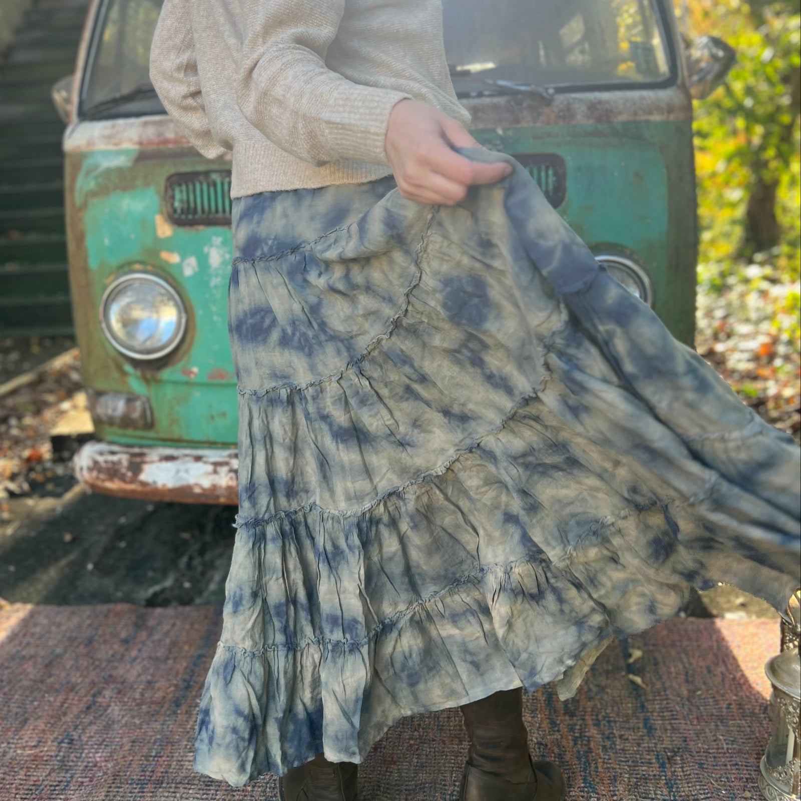 Someone wearing the indigo Tie Dye Gauze Cotton Skirt with a beige sweater in front of a vintage teal Volkswagen bus. Showing off the back.