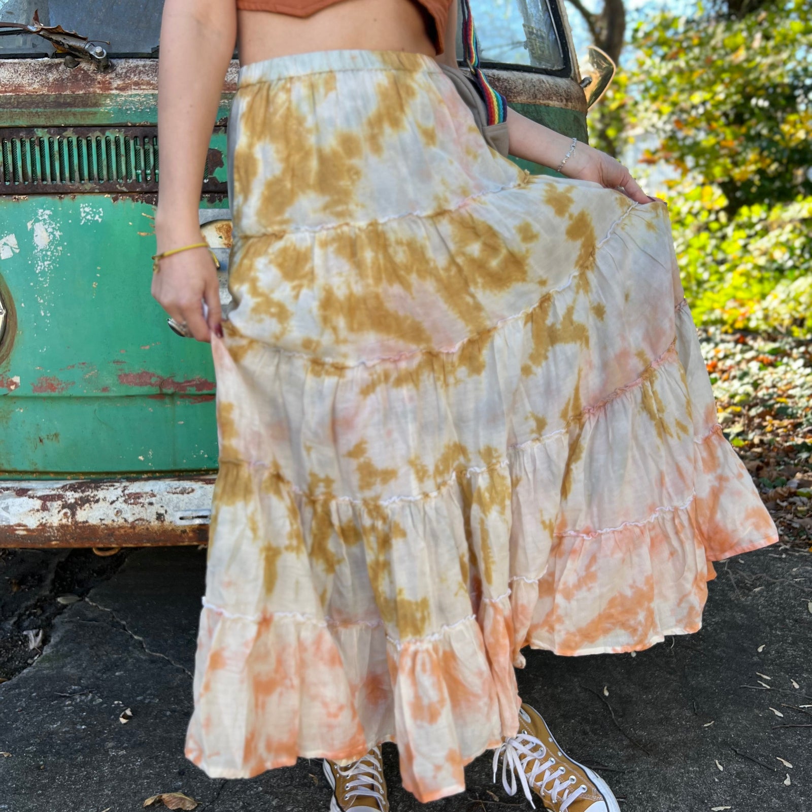 Someone wearing the sand Tie Dye Gauze Cotton Skirt with a burnt orange vest in front of a vintage teal Volkswagen bus.