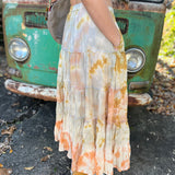Someone wearing the sand Tie Dye Gauze Cotton Skirt with a burnt orange vest in front of a vintage teal Volkswagen bus.