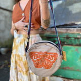 A woman holding the butterfly Bohemian Round Print Cotton Crossbody Bag in front of herself.