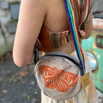 A woman wearing the butterfly Bohemian Round Print Cotton Crossbody Bag in front of herself.