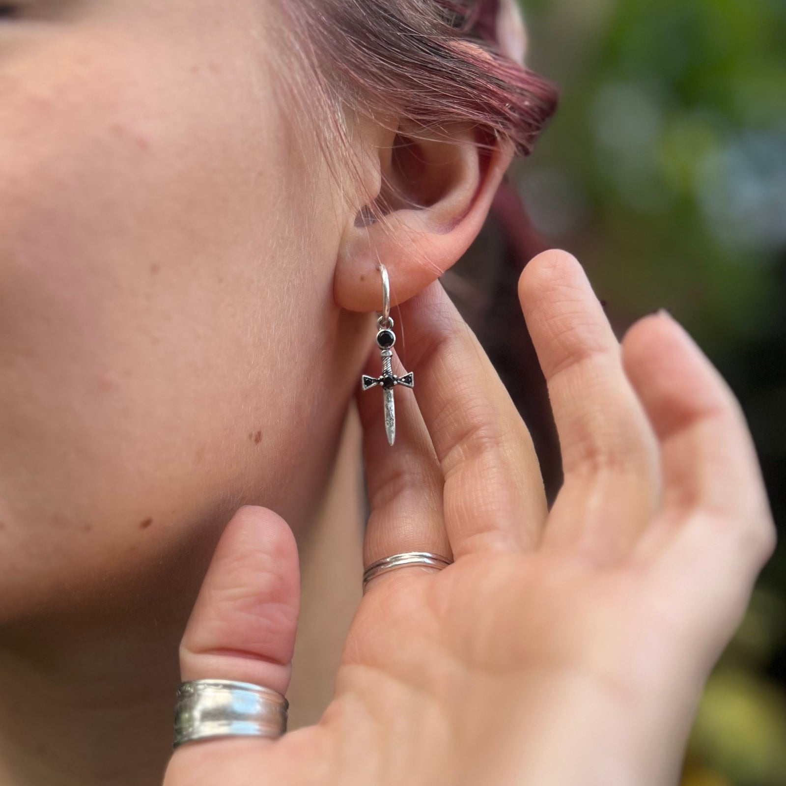 A woman wearing the Silver Sword Hoop Earrings.