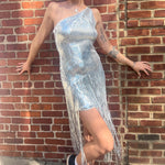 A woman wearing the Silver Sequin Disco Dress in front of a brick building.