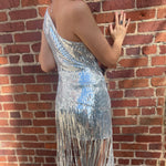 A woman wearing the Silver Sequin Disco Dress in front of a brick building.