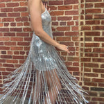 A woman wearing the Silver Sequin Disco Dress in front of a brick building.