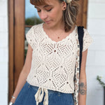 A woman wearing the natural Boho Knit Sweater Crochet V-Neck Top with some denim pants.