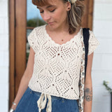 A woman wearing the natural Boho Knit Sweater Crochet V-Neck Top with some denim pants.