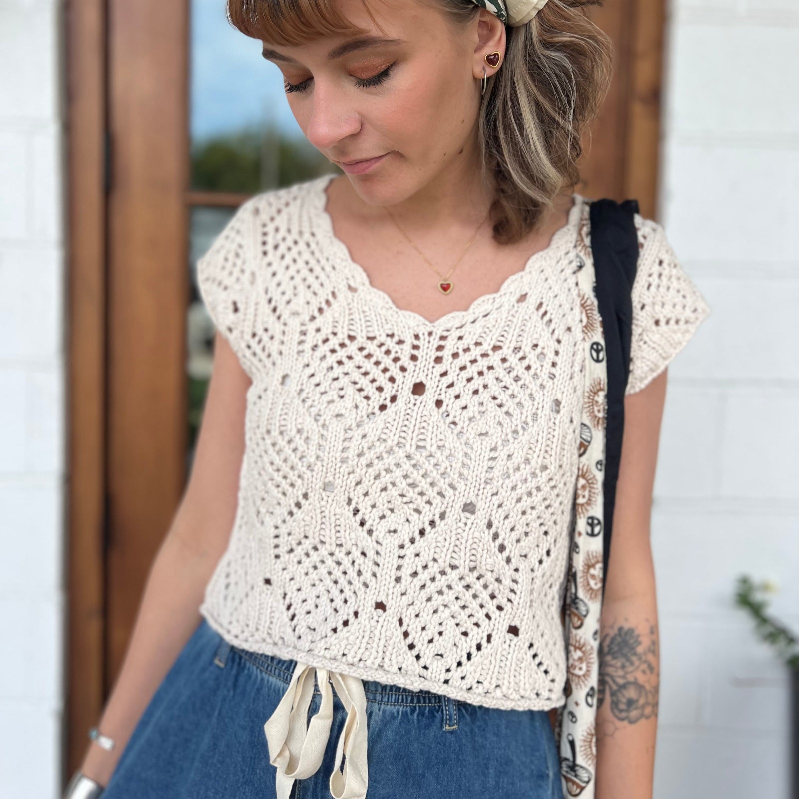 A woman wearing the natural Boho Knit Sweater Crochet V-Neck Top with some denim pants.