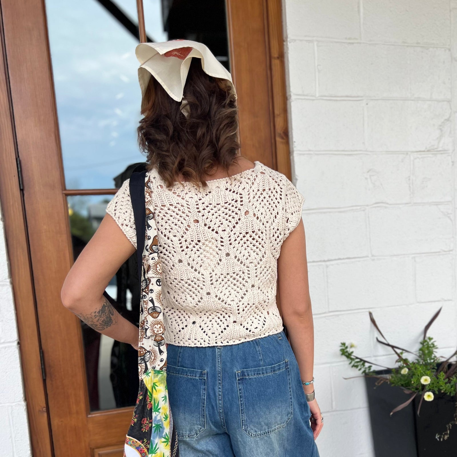 A woman wearing the natural Boho Knit Sweater Crochet V-Neck Top with some denim pants.