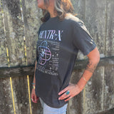A woman wearing the Huntrix Kpop Demon Hunters Inspired Cotton Tee with jeans in front of a wooden fence, showing off the side.