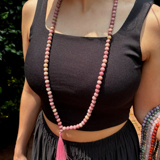 model wearing a black tank top with a pink thulite mala