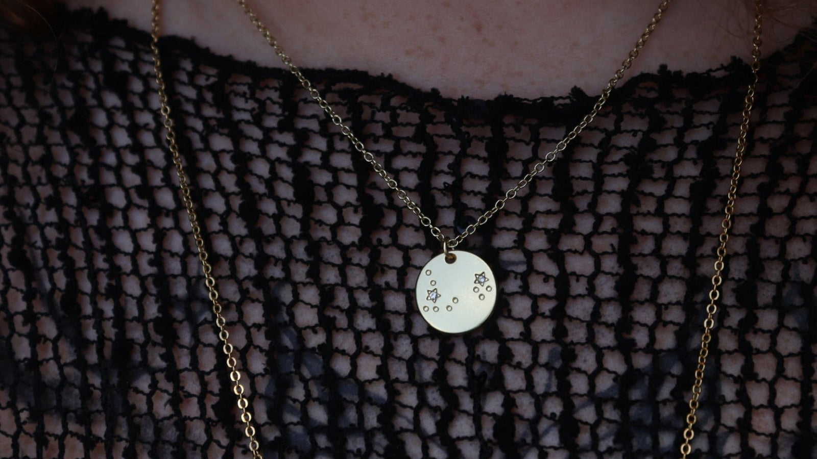 Someone wearing the Pisces 14k Gold Dipped Nickel-Free Zodiac Necklace with a black net top.