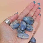 Blue Kyanite tumbles in palm for scale