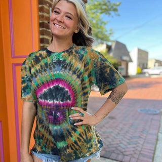 Woman modeling psychedelic mushroom-eye tie-dye t-shirt in front of orange door