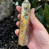 Pyrite Crystal Tower in hand over mulch