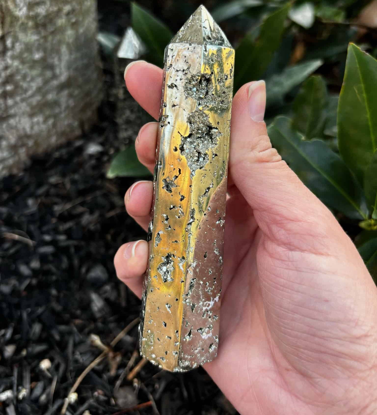 Pyrite Crystal Tower in hand over mulch