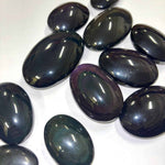 Polished rainbow obsidian palm stones reflecting light to reveal hidden color bands